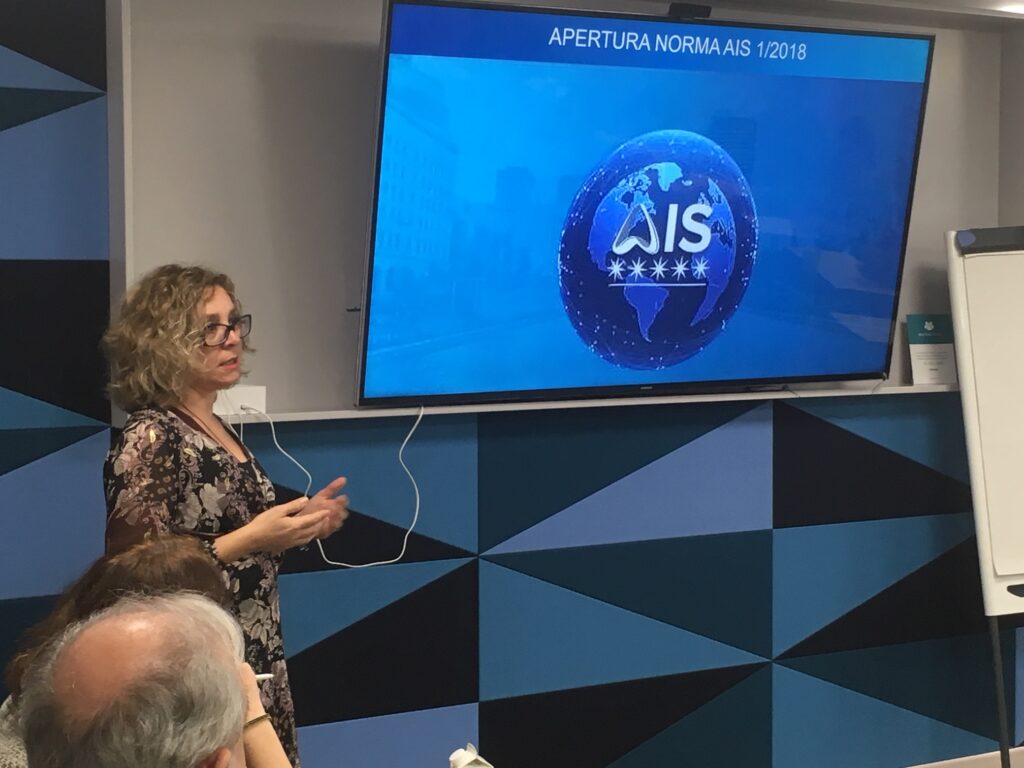 Rosa Rodríguez habla junto al logo de AIS