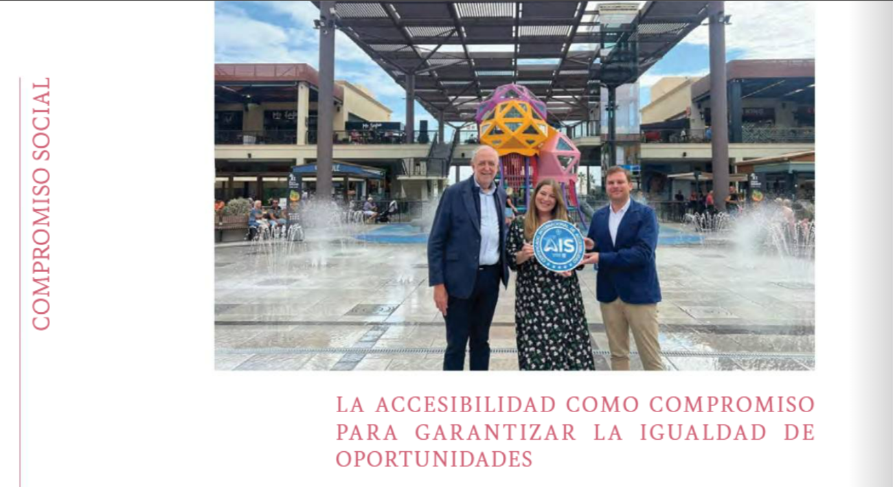 Tres personas posan en una plaza pública con fuentes, sosteniendo un distintivo AIS de accesibilidad, en un entorno comercial al aire libre.